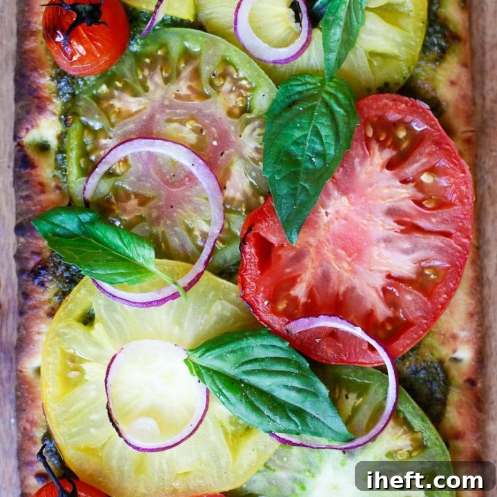 A beautiful vegan pizza with heirloom tomatoes and basil pesto, freshly baked and ready to serve.