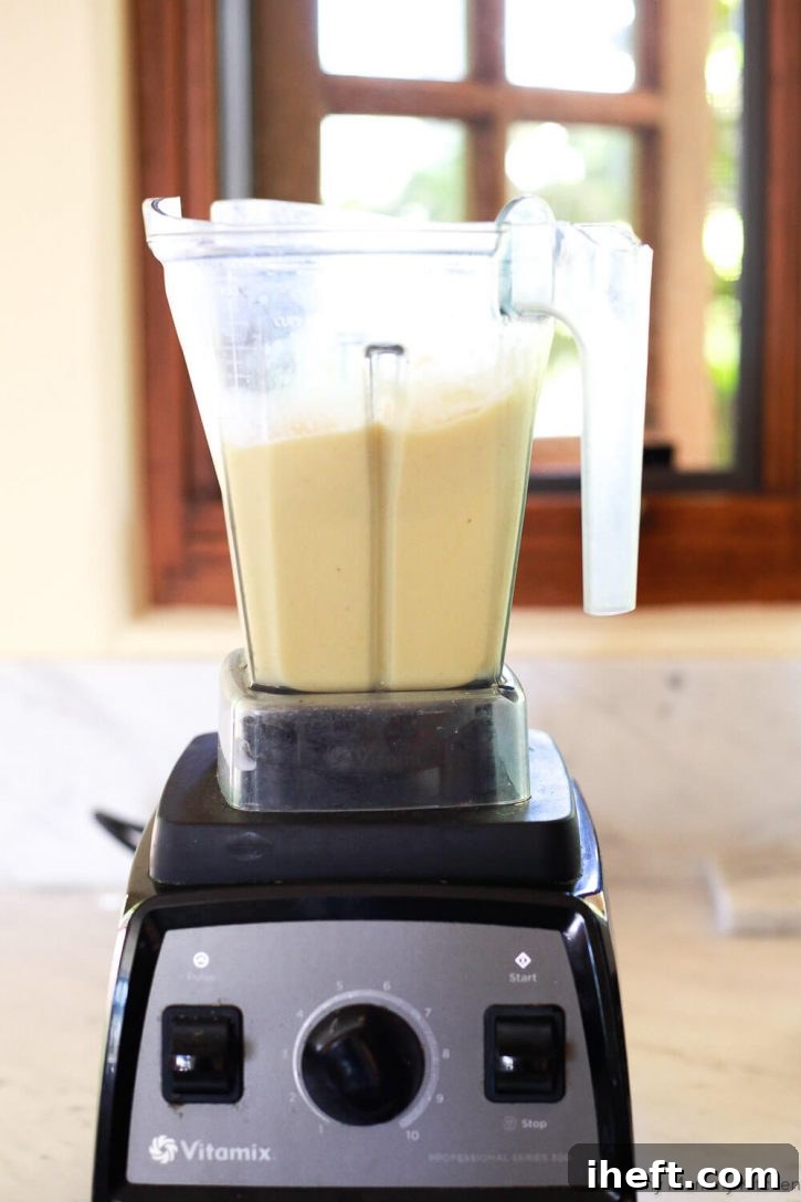A creamy pineapple banana smoothie is being blended to perfection in a Vitamix blender, highlighting its smooth and thick texture.
