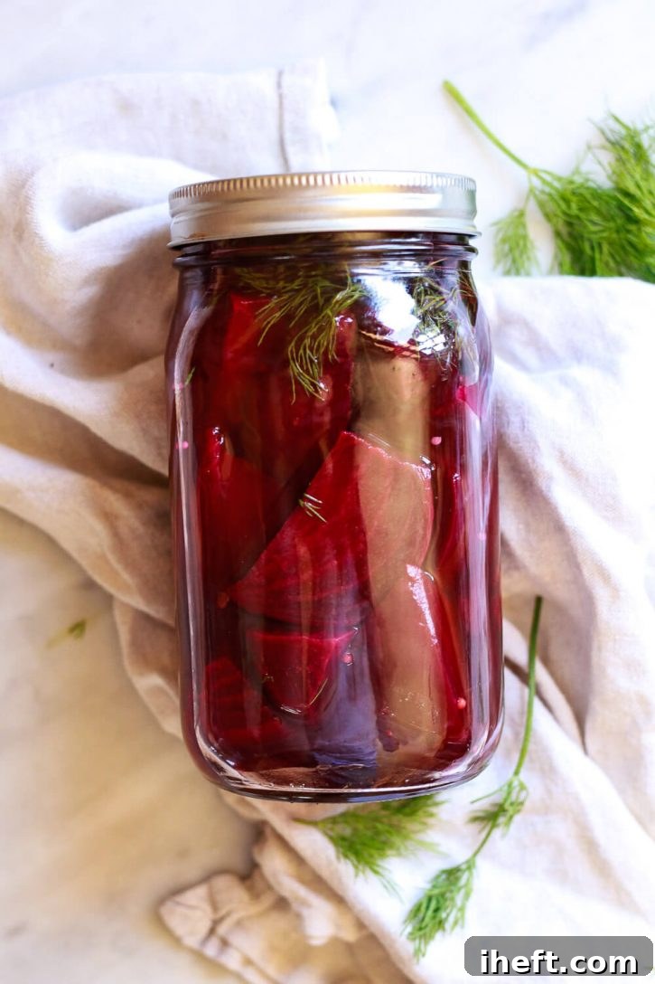 A beautiful jar of homemade quick pickled beets sitting on a marble countertop, ready for refrigeration.