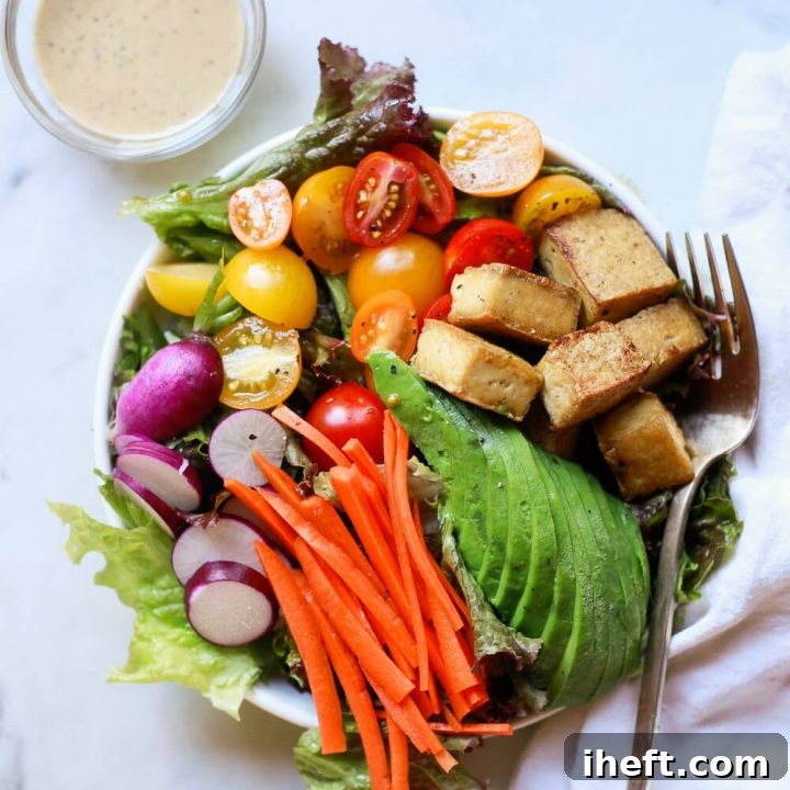 A beautiful salad topped with perfectly cooked tofu, creamy avocado slices, vibrant tomatoes, and crisp carrots. A versatile and healthy way to enjoy tofu.