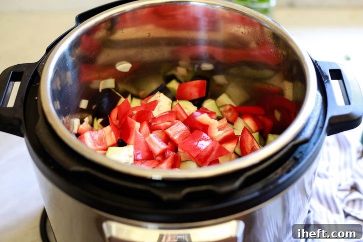 Red bell peppers, tender eggplant, and sweet onions layered within an Instant Pot, ready to become delicious ratatouille.