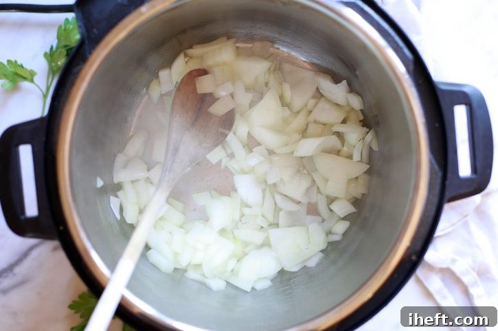 Diced onions are sautéing in an Instant Pot pressure cooker, forming the flavor base for the risotto.