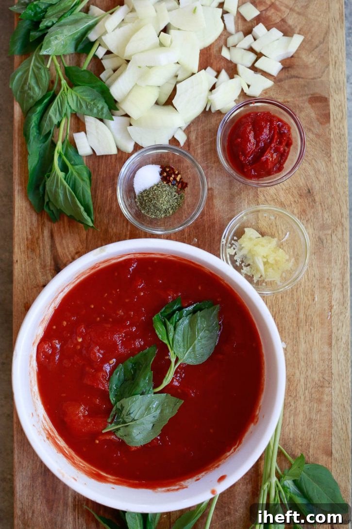 The ingredients for an easy simple Instant Pot spaghetti sauce on a cutting board: tomatoes, spices, garlic, onion, tomato paste, and fresh basil. 