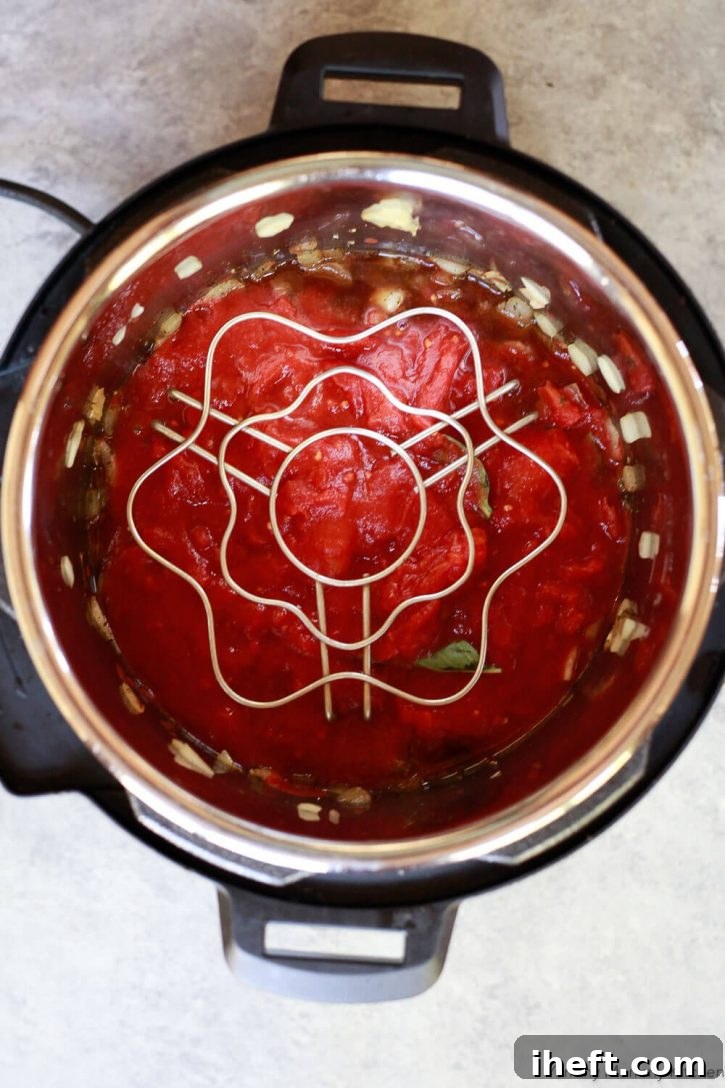 How to make Instant Pot spaghetti sauce. All the ingredients for Instant Pot spaghetti sauce are in a pressure cooker. A trivet is on top to cook a spaghetti squash with the pot in pot method. 