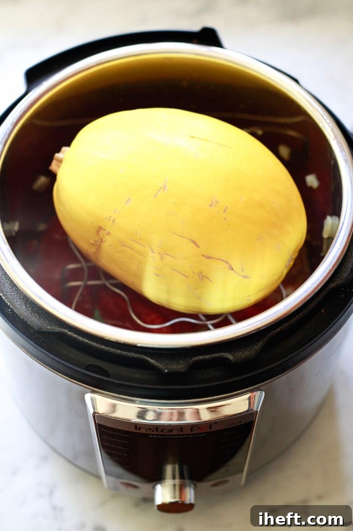 A whole spaghetti squash sits on a trivet on top of homemade spaghetti sauce in an Instant Pot. 