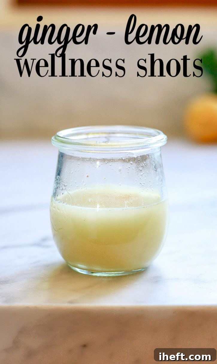 A small glass jar filled with a yellow ginger shot or wellness shot. 