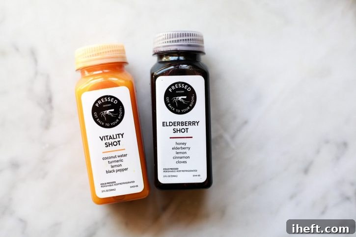Wellness shots from Pressed Juicery on a marble countertop. Turmeric Vitality shot and Elderberry shot. 