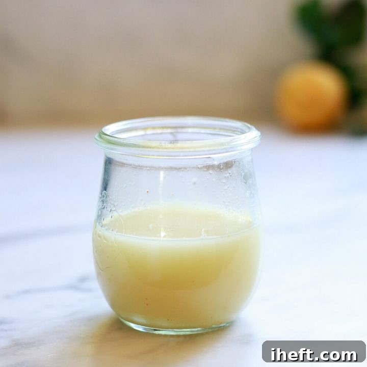 A small jar filled with a ginger shot sits on a countertop.