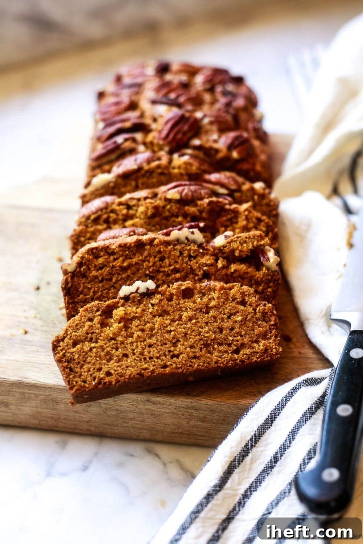 A loaf of healthy, dairy free, eggless whole wheat vegan pumpkin bread sliced on a cutting board. 