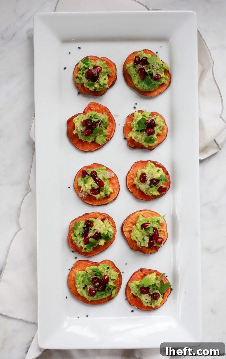 A platter filled with avocado sweet potato toast crostini topped with pomegranate, finger lime, and cilantro. Sweet potato crostini is a healthy vegan appetizer recipe. 