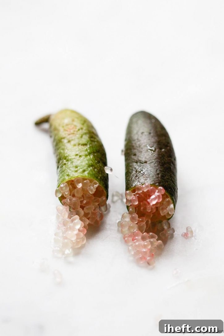 A close-up photo of caviar limes, or finger limes, cut in half with pink lime juice caviar spilling out. 