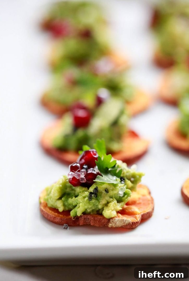 A slice of sweet potato toast (crostini) with avocado, pomegranate, and cilantro. A healthy vegan appetizer recipe. 