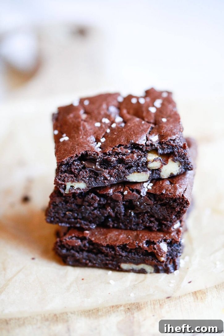 A perfectly stacked trio of fudgy vegan brownies, showcasing their irresistible crackly tops. This image highlights how to make the BEST dairy-free and eggless brownies.