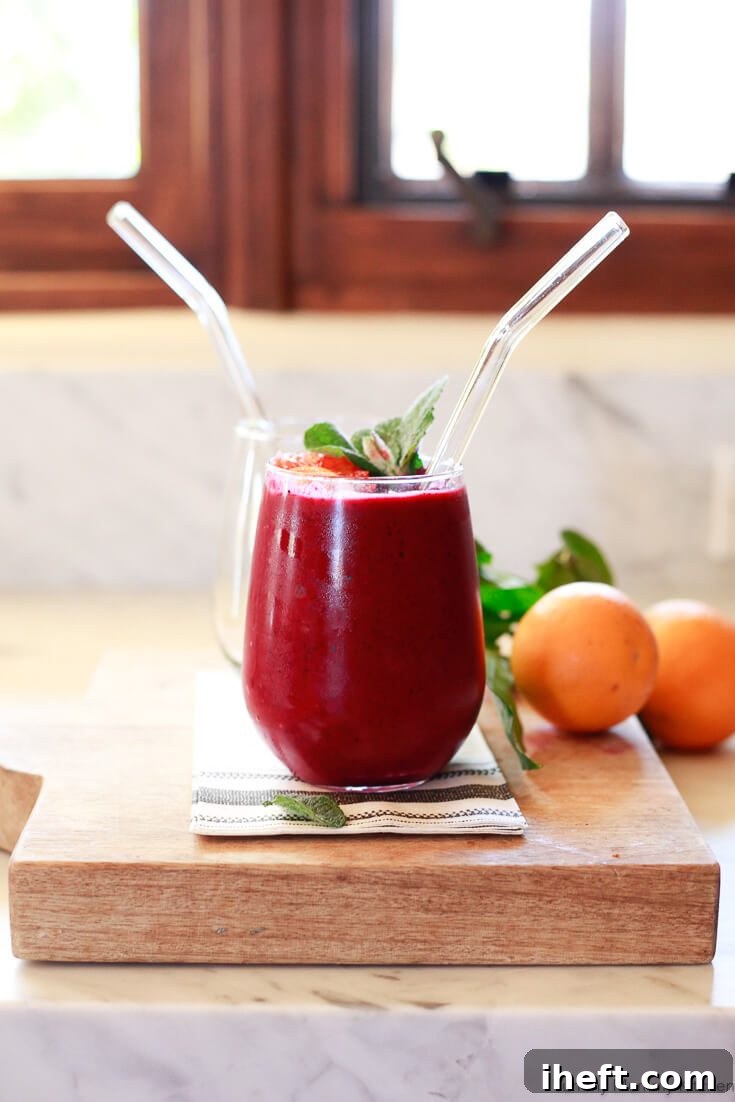 A vibrant glass of a delicious beet smoothie recipe, artfully blended with fresh orange and mixed berries, made with raw beets, ensuring it's exceptionally high in Vitamin C, potent antioxidants, and boasts significant anti-inflammatory properties.