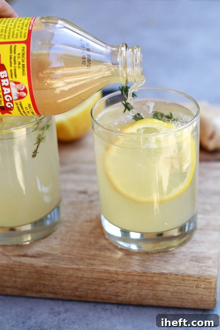 A bottle of Bragg apple cider vinegar is being poured into a glass of lemon water, creating a healthy and tasty apple cider vinegar detox drink specifically designed for natural body cleansing and supporting weight loss efforts.