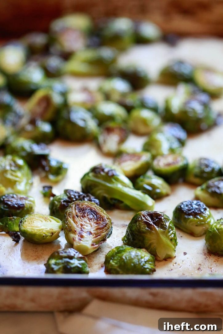 A sheet pan filled with perfectly crispy roasted Brussels sprouts, golden-brown and ready to be glazed, showcasing ideal oven roasting results.