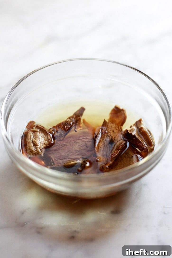Dried porcini mushrooms soaking in a small bowl of hot water, illustrating a key step for enhancing the gravy's umami flavor.