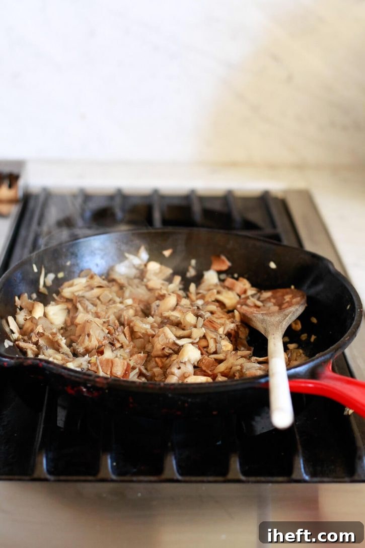 Wild mushrooms, shallots, and garlic gently sautéing in a cast iron skillet, building a fragrant and savory base for the vegan mushroom gravy.