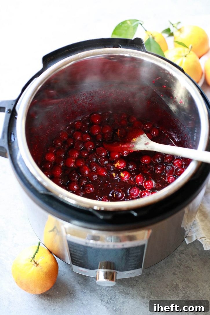 An open Instant Pot pressure cooker proudly displays a batch of homemade fresh cranberry sauce, its vibrant red color and chunky texture promising deliciousness. The image highlights the ease and convenience of making Instant Pot cranberry sauce for holiday meals.