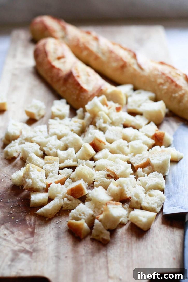 Close-up shot of two sourdough baguettes expertly cut into uniform cubes, ready for toasting to become the foundational component of a delicious homemade Thanksgiving stuffing.