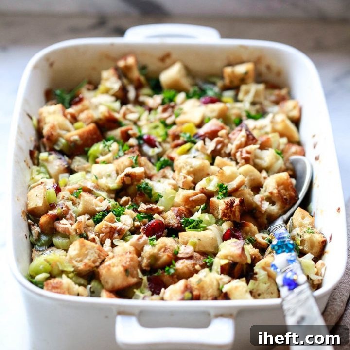 Perfectly baked vegan stuffing, golden and crispy on top, garnished with fresh parsley and toasted pecans, ready to be served from a festive casserole dish.