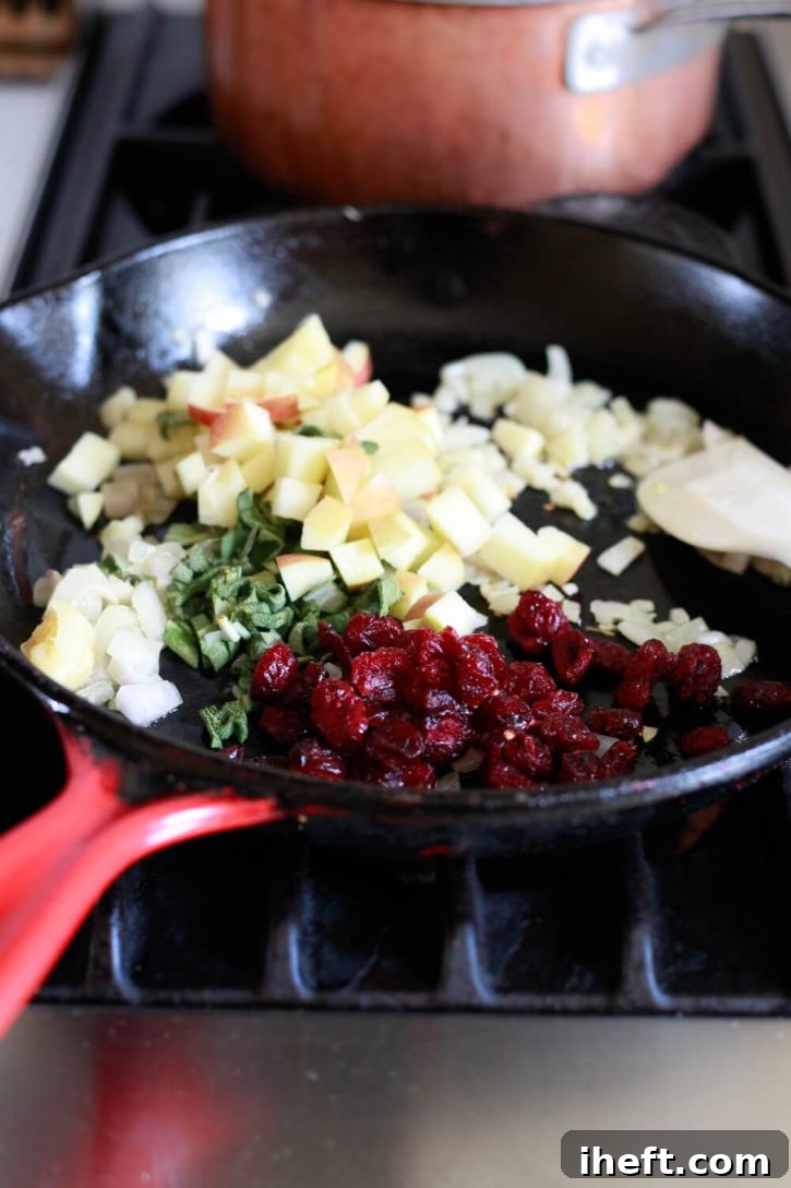 A mix of dried cranberries and minced garlic being added to a skillet with sautéed shallots, infusing warm, sweet, and pungent flavors into the dish.