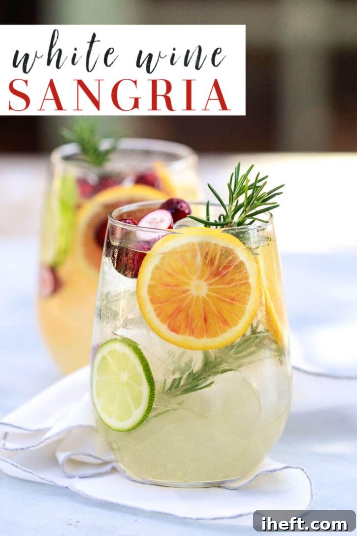 A beautiful glass of white sangria, elegantly garnished with vibrant orange and lime slices, and a fragrant sprig of rosemary. This easy white wine sangria recipe is a perfect and refreshing choice for fall and winter gatherings.