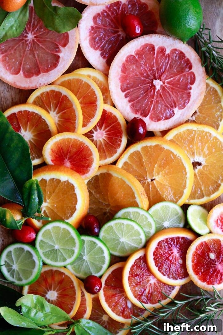 A vibrant and beautiful close-up photo of various sliced citrus fruits, including ruby red grapefruit, deep blood oranges, bright regular oranges, and zesty limes, perfectly prepped for making a delicious pitcher of white sangria.