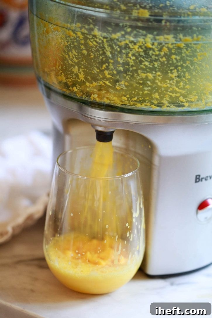 A high-speed capture of turmeric and orange juice being extracted from a powerful Breville juicer, illustrating the dynamic process of making homemade turmeric wellness shots.