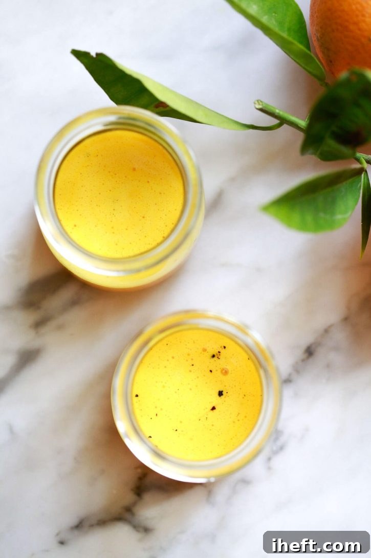 A beautiful presentation of a simple turmeric shot recipe, showcasing the benefits of this golden elixir. Two homemade turmeric shots sit elegantly on a pristine marble kitchen counter, inviting wellness.
