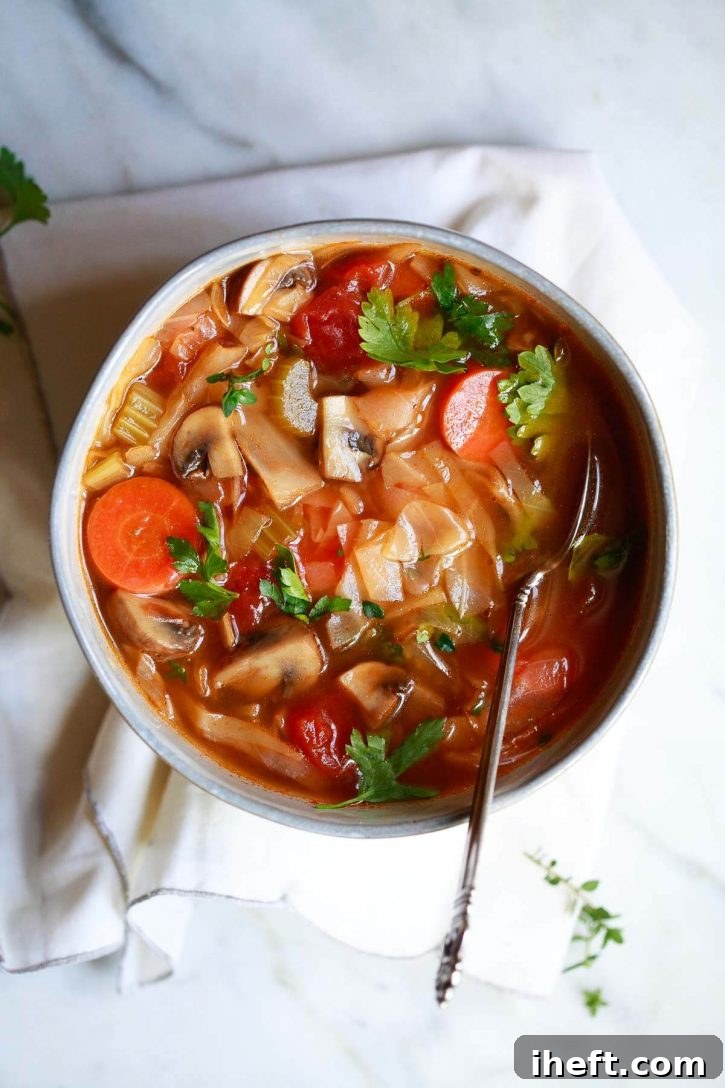A steaming bowl of healthy detox cabbage soup, garnished with fresh herbs. This updated recipe for weight loss combines nutritious vegetables and tender cabbage.