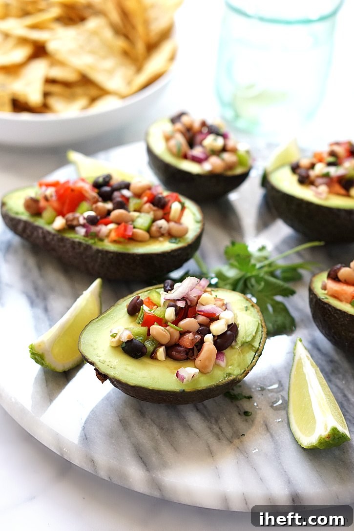 Colorful Cowboy Caviar dip with black beans, black-eyed peas, sweet corn, bell peppers, and fresh avocado chunks, served with tortilla chips.