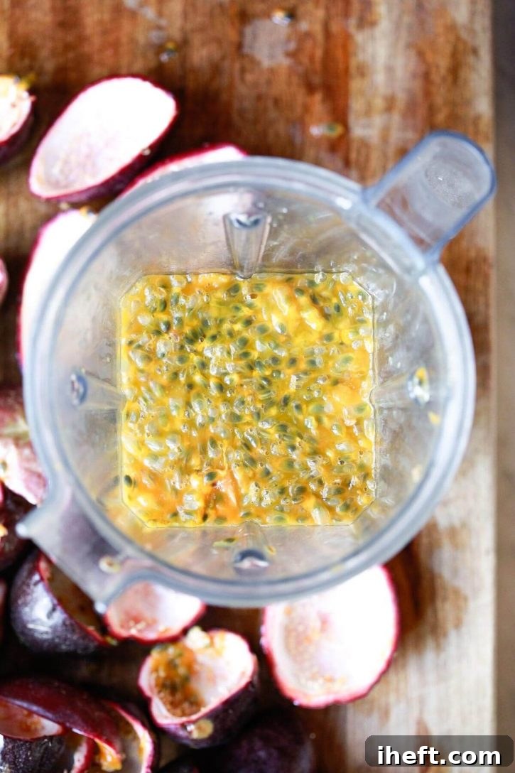 Passion fruit pulp and seeds are scooped into a Vitamix blender, ready to be transformed into juice.