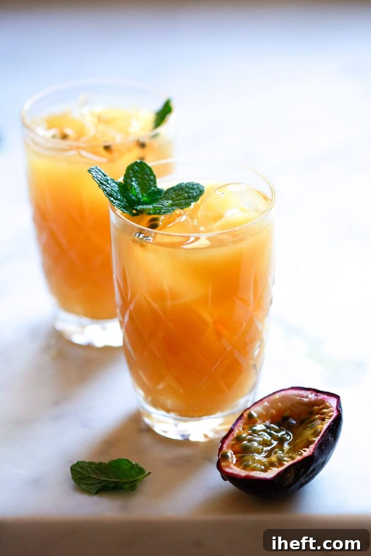 Crystal glasses filled with sparkling homemade passion fruit juice, elegantly garnished with a few passion fruit seeds and fresh mint leaves.