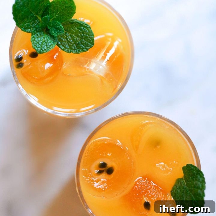 A glass of freshly made passion fruit juice with a halved passion fruit and mint garnish.