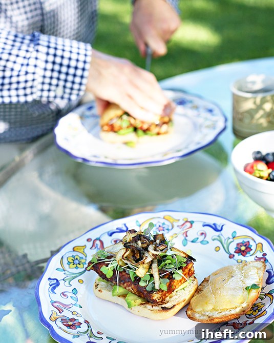 Two vegetarian tempeh cheeseburgers with caramelized onions on dinner plates. 
