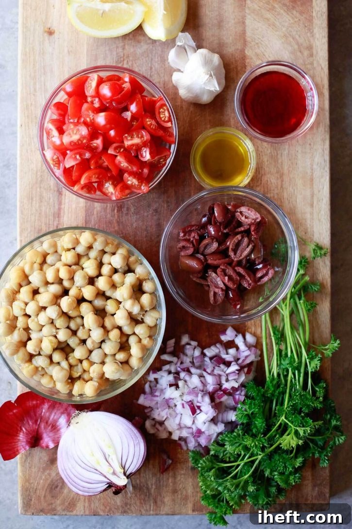The vibrant ingredients for Balela, a Middle Eastern bean salad, neatly arranged in bowls on a rustic cutting board, showcasing fresh tomatoes, olives, red onion, garlic, and parsley.