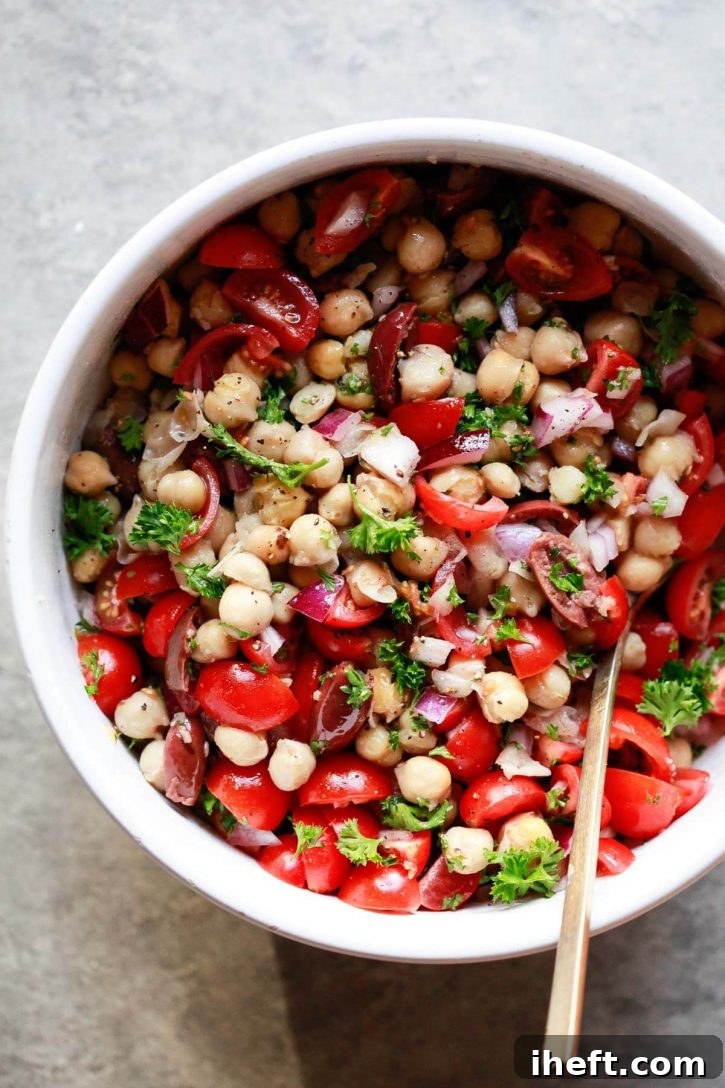 A beautiful white bowl filled with Balela, a Middle Eastern chickpea and bean salad featuring tomatoes, herbs, olives, and red onions. This healthy, vegetarian, vegan, and gluten-free recipe is ready to serve.