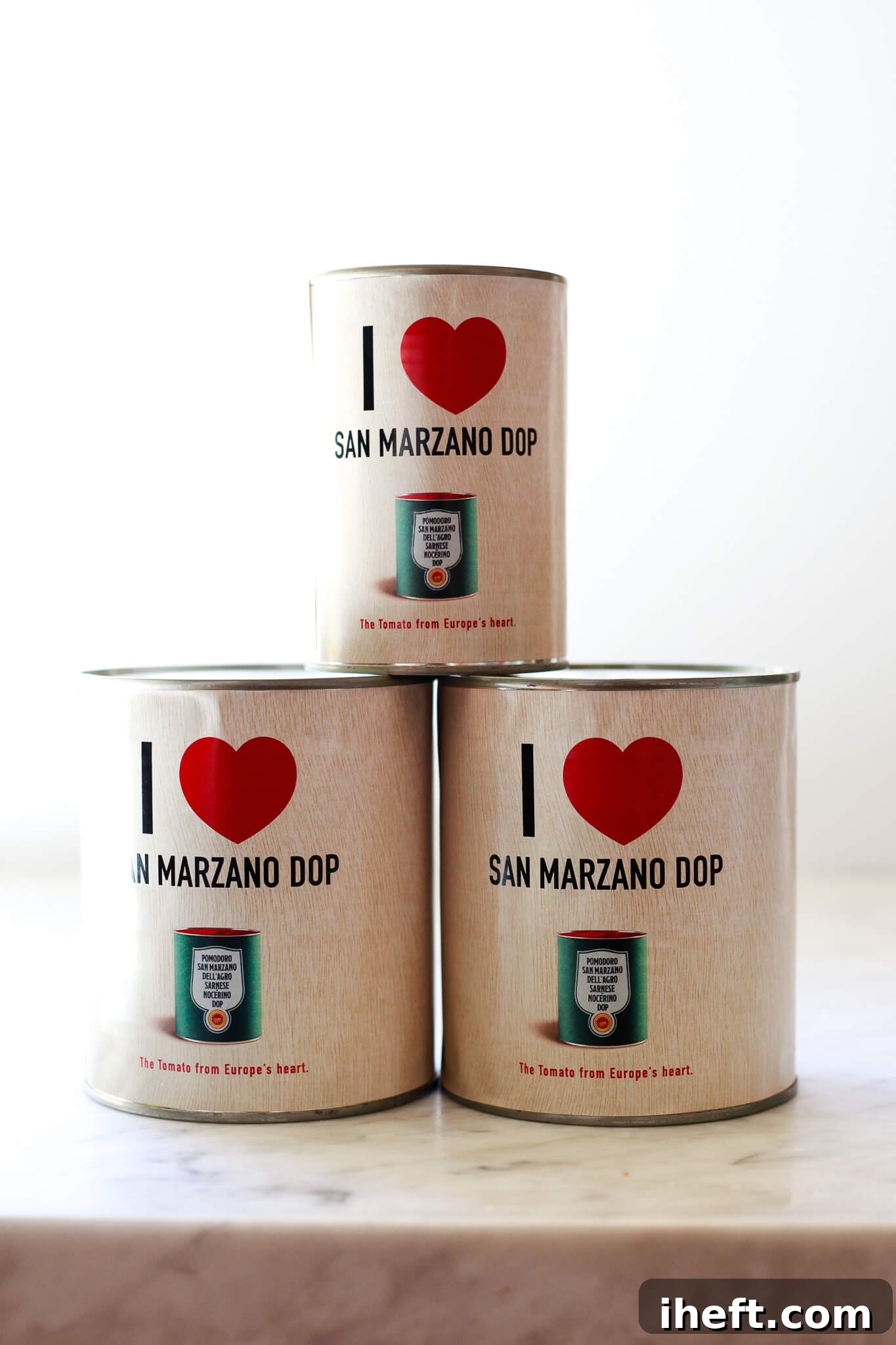 A trio of classic San Marzano DOP tomato cans, emphasizing quality Italian pantry items.