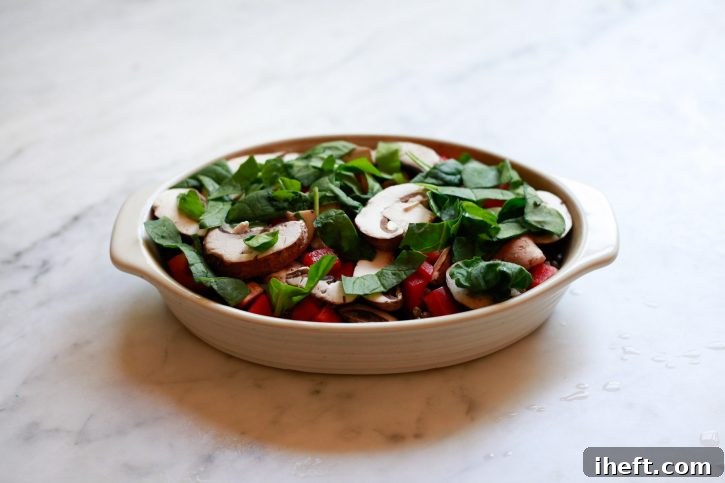 Lentils, bell pepper, mushrooms, and spinach are layered in a casserole dish to make a delicious healthy lentil bake. 