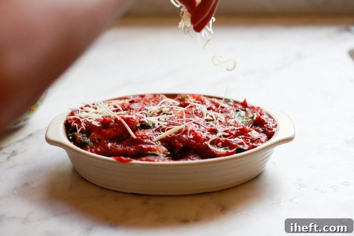 Mozzarella cheese is sprinkled over a vegetarian casserole before baking. 