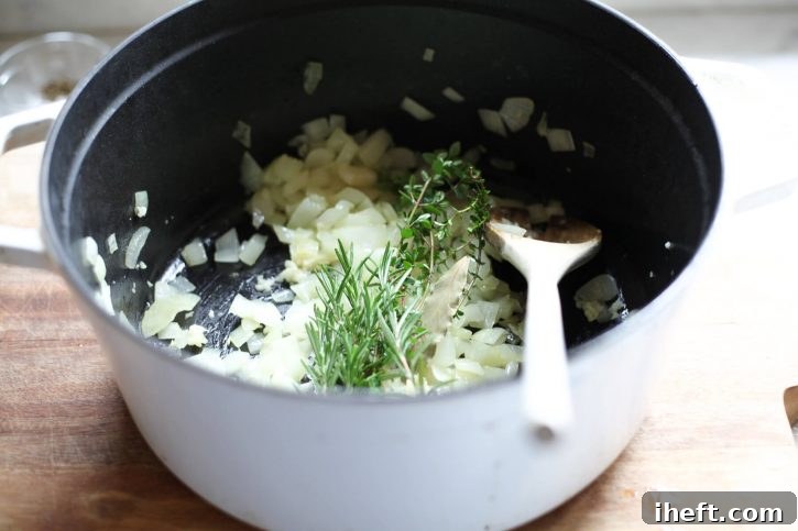 Garlic and herbs are added to a pot while making garbanzo bean vegetable soup. 