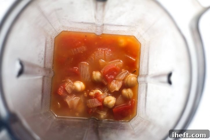 A cup of chickpea and tomato soup in a blender. 