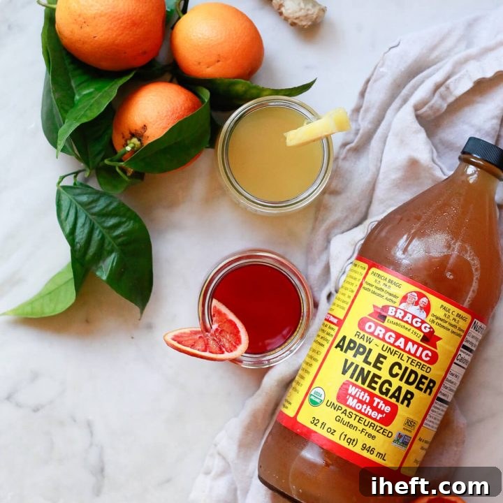 Two homemade apple cider vinegar shots, one orange and one pineapple flavored, in small glass jars, showcasing their vibrant colors and fresh appeal. They are perfect for daily wellness, immune support, and detox.