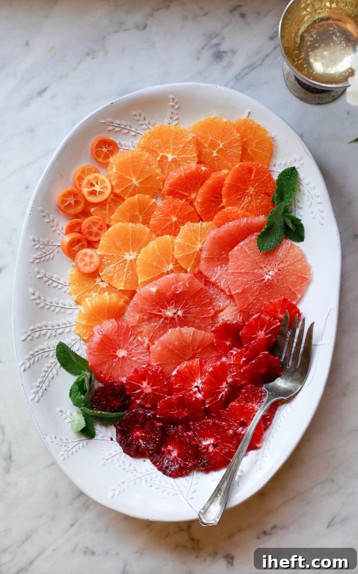 A beautifully arranged citrus fruit salad on a white oval serving platter, featuring kumquats, oranges, tangerines, grapefruit, and blood orange round slices. This colorful, healthy, and easy fruit salad is perfect for any brunch occasion.