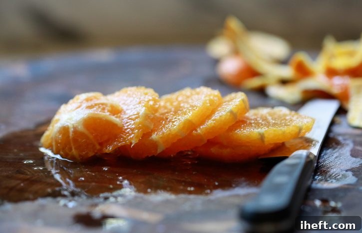 A freshly peeled orange has been skillfully cut into uniform round slices, showcasing its natural beauty and readiness for a vibrant fruit salad presentation.