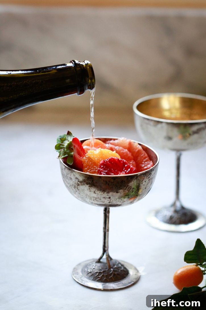 Champagne or prosecco is elegantly poured over vibrant slices of citrus, including refreshing grapefruit, sweet orange, and rich blood orange, served in tall Champagne coupes, creating a festive Mimosa Fruit Salad.