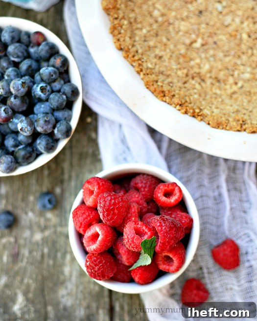A close-up shot of the vibrant red, white, and blue ice cream pie, showcasing the fresh raspberries and blueberries along with the inviting texture of the granola crust.