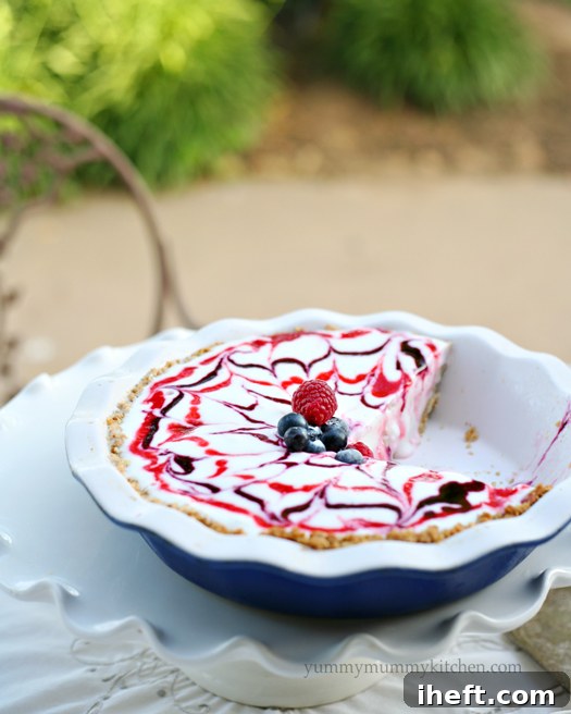 A stunning shot of the Red, White, and Blue Ice Cream Pie, showing the intricate swirls of berry sauces over vanilla ice cream, all nestled within a crunchy granola crust, ready for a festive celebration.