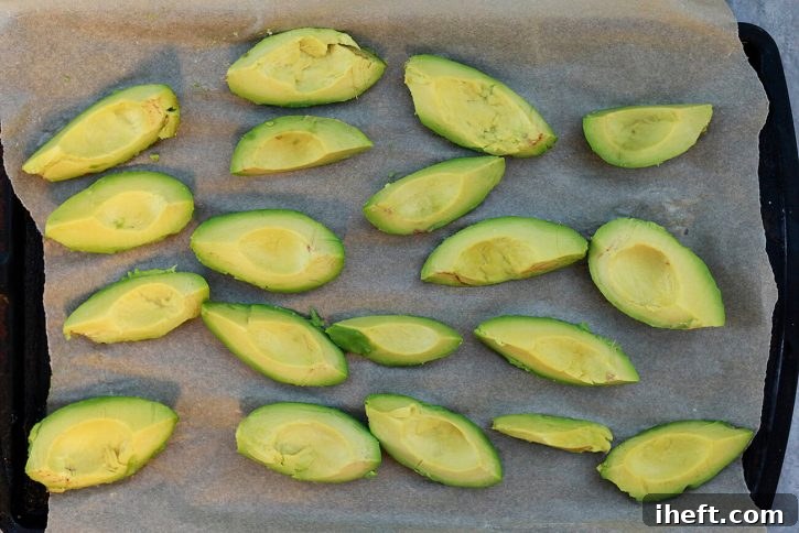 Avocado pieces thoughtfully arranged in a single layer on a parchment-lined cookie sheet, undergoing initial flash freezing.